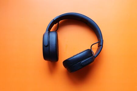 top view of black color headphone on orange tableの写真素材