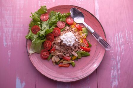 top view of fresh salad on plate on pink background.の写真素材