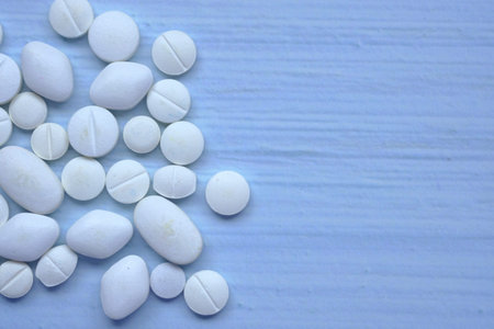 close up of pink pills spilling from container isolated in whiteの写真素材