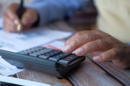 Close up of senior man using calculatorの写真素材