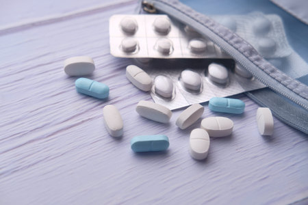 close up of white pills spilling on a white background