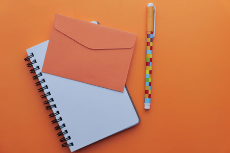 orange color envelope, pen and notepad