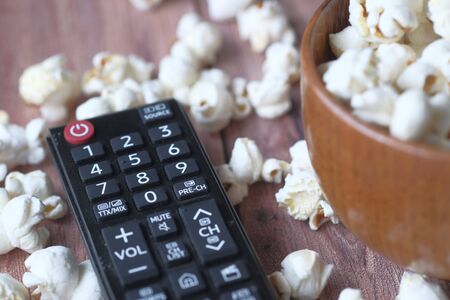 Close up of tv remote and popcorn on tableの写真素材