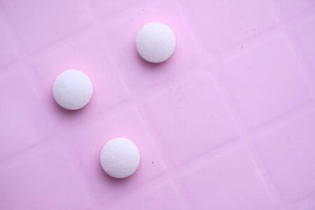 close up of white pills spilling on a white backgroundの写真素材