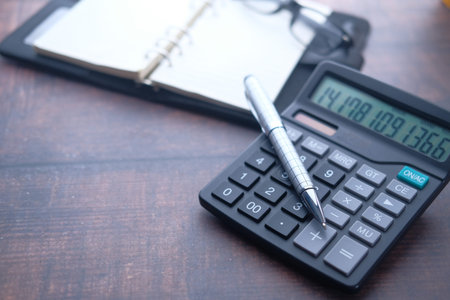 Close up of pen on calculator , notepad on black background.