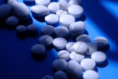 close up of white pills spilling on a pink backgroundの写真素材