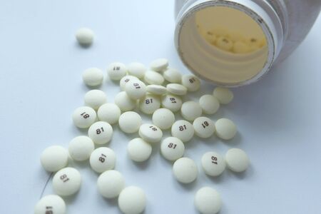 close up of white pills spilling on a white backgroundの写真素材