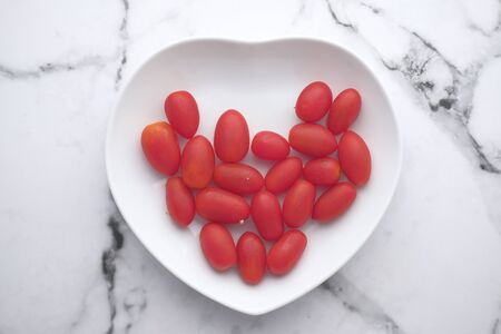 fresh red cherry tomato on heart shape plate .の写真素材