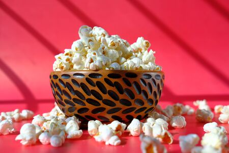 popcorn in a wooden bowl in a red backgroundの写真素材