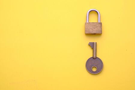 top view of padlock and key on yellow backgroundの写真素材