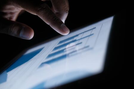 Close up of man hand analyzing chart on digital tabletの写真素材
