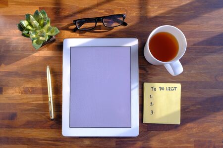top view of digital tablet, tea and notepad on wooden tableの写真素材