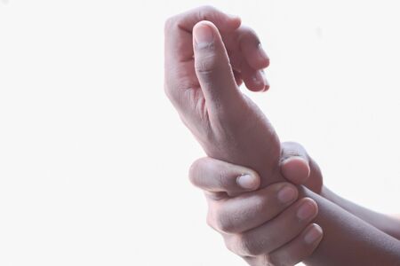 Close up of man hand suffering wrist pain isolated in white.の写真素材