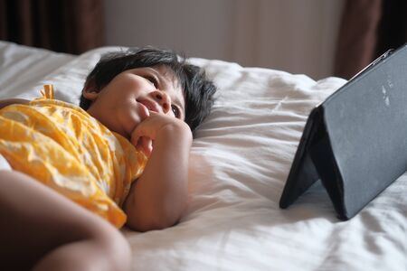 Close up of baby child use digital tablet laying on bedの写真素材