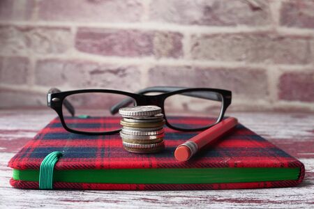 Close up of coins, notepad and pencils on tableの写真素材