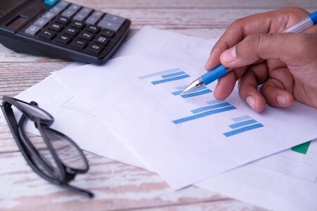 close up of person hand analyzing chart on office deskの写真素材