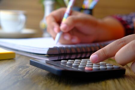 Close up of women hand use calculator and writing.の写真素材