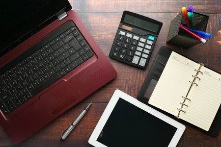 top view of digital tablet laptop, calculator and notepad on wooden table .の写真素材