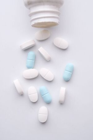 close up of white pills spilling from a container .の写真素材