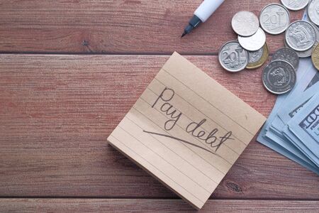 pay debt word written on notepad with pen on tableの写真素材