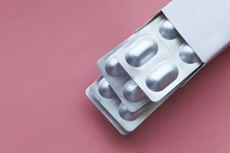 top view of blister pack in a paper box on pink backgroundの写真素材