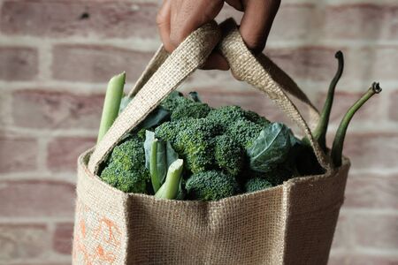 Mans hand hold eco friendly reusable bag with various fresh organic vegetablesの写真素材
