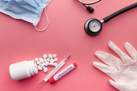 Close up of face mask , blood test tube and thermometer on red backgroundの写真素材