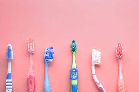 Many colorful toothbrushes on pink background, top view.
