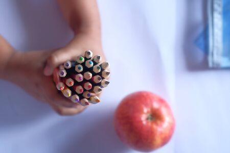 top view of child hand holding color pencils on tableの写真素材