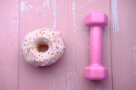 A donut and a dumbbell on pink backgroundの写真素材