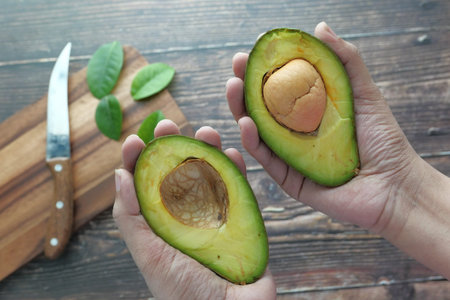 Half avocado fruit holding by hand, healthy fruit