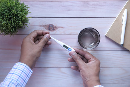man hand holding thermometer on wooden background