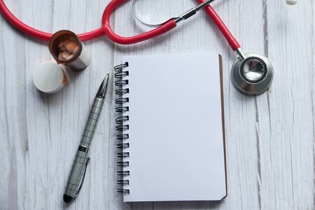 Stethoscope, sticky notes, notepad or notebook, pen on wooden tableの写真素材