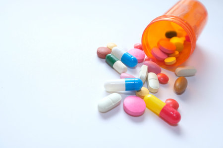 multi color pills spilling from container , close up