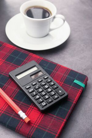 pencils, calculator notepad, and tea t on table at early morningの写真素材