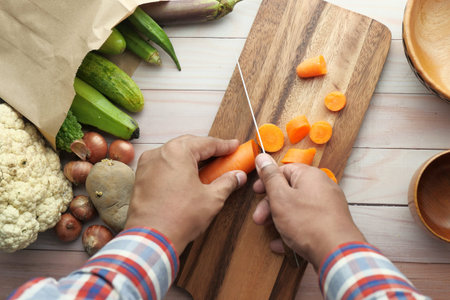 top view of man hand cutting carrot on chopping board