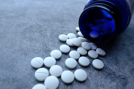 colorful pills spilling on orange background, top view