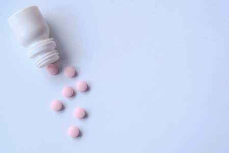 pink color pills spilling on white background, top view