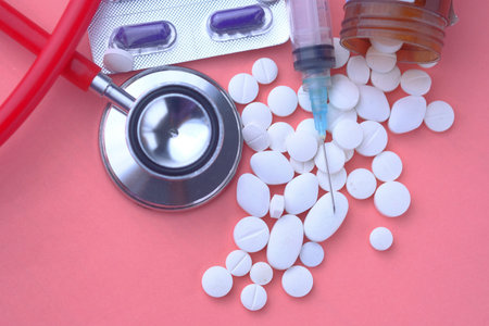 Assorted medical drugs, stethoscope and syringe on color background.