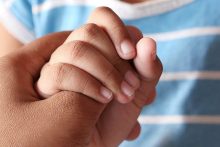 father and little son holding hands, close up.