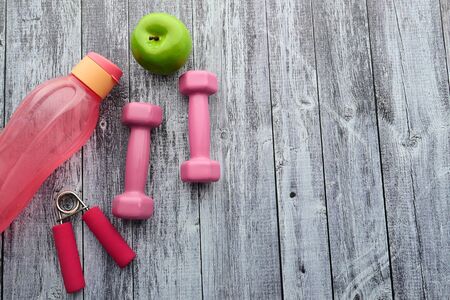 Fitness concept with bottle of water and apple,dumbbells on wooden background.の写真素材