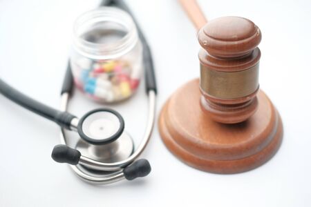 Close up of gavel and pills on white backgroundの写真素材