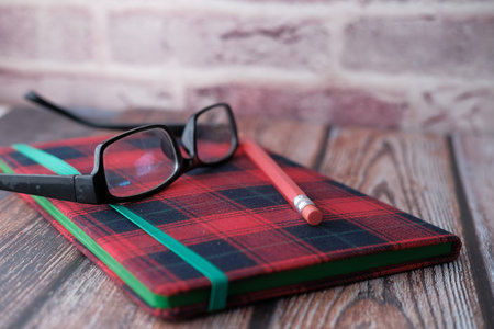 Close up of notepad, pencils, eyeglass on table