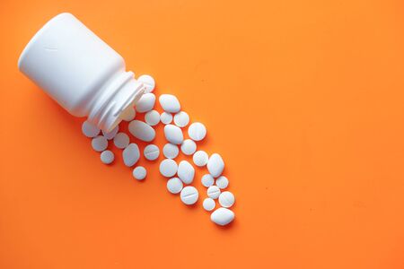 drugs and capsule spilling from container on color backgroundの写真素材