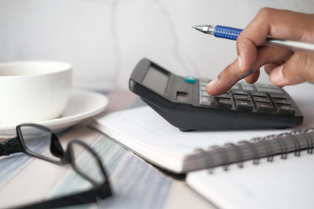 Close up of man hand using calculator and financial chart on table
