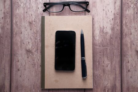 top view of smart phone and pen on notepadの写真素材