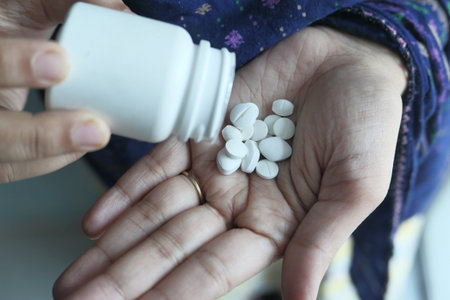 close up of white pills on palm of women hand