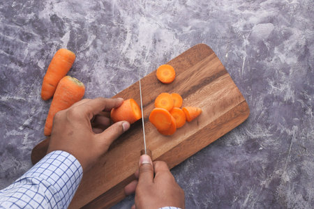 high angle view of young man cutting carrot