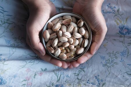 high angle view of women holding bowl of pistachiosの写真素材