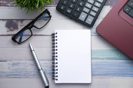 high angle view of notepad, laptop and calculator on tableの写真素材